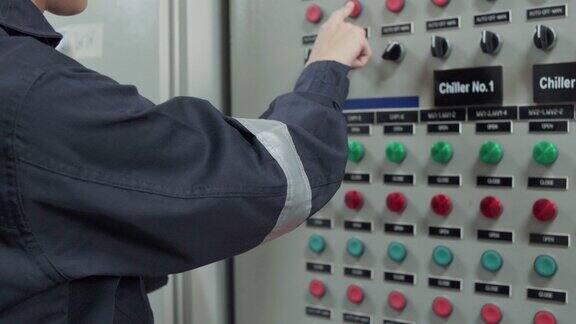 一名电工工程师在工业厂房控制室、操作员站网络中工作检查和记录电气保护继电器参数