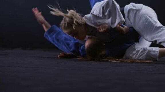 SLOMO女柔道运动员在白色的服装扔她的对手在蓝色的地板上