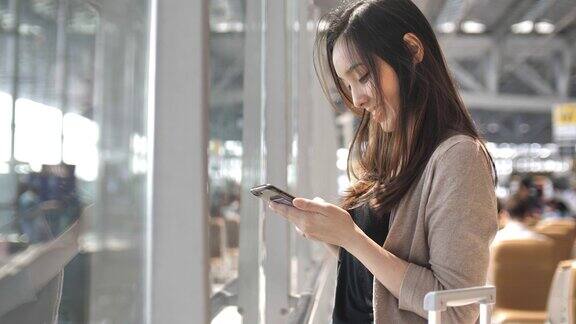 亚洲年轻女子在等待航班时触摸智能手机慢镜头