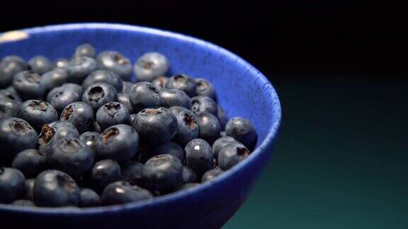 陶瓷碗的特写满蓝莓在蓝色的背景成熟蓝莓板有机健康食品