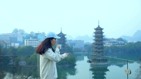 在中国桂林市中心年轻的女子一边喝着咖啡一边看着宝塔