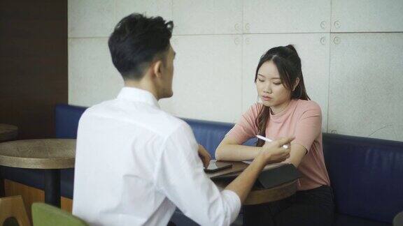 亚洲华人年轻商人在咖啡馆向他的客户解释投资计划