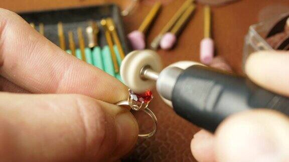 珠宝商正忙着在金戒指上切割一块宝石专业的珠宝商会用一种特殊的工具来打磨金戒指上的红色宝石由专业珠宝商对宝石进行加工、抛光