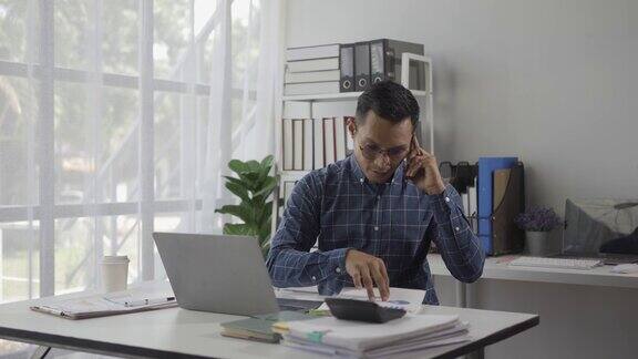 穿着正装与顾客或朋友交谈的快乐、积极的商人坐在现代办公室里用智能手机和同事聊天