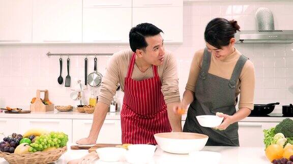 一对亚洲夫妇在厨房边准备健康食物边聊天