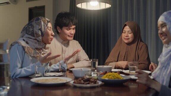 快乐的亚洲穆斯林家庭与表姐遥望镜头视频在线庆祝斋月晚餐一起在家里两代人一起庆祝开斋节