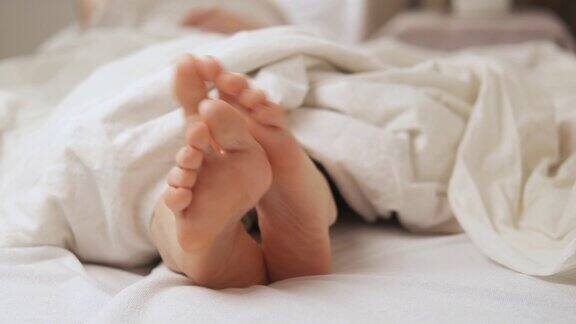 床上盖着白毯子女人的脚发痒足部疾病、真菌