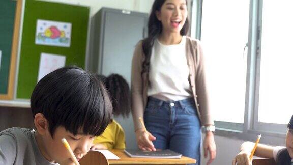 亚洲学校的老师在课堂上帮助学生年轻女子在学校工作帮助男孩写作教育支持和关心