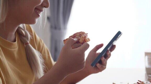 亚洲女人喜欢在家里用智能手机吃披萨和不健康的食物