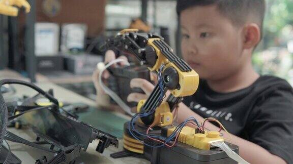 教育主题:男孩控制机器人手臂在数字平板科学工程教育技术