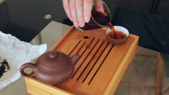 中国茶道取玻璃器皿将热茶倒入陶制碗中在茶板上冲泡中国茶4k慢动作