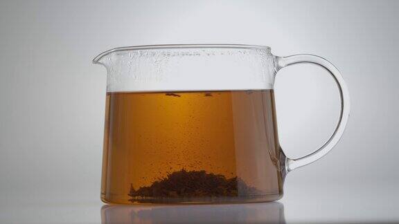一壶热红茶在热水中混合后冲泡茶叶孤立在灰色背景