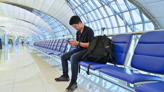 亚洲男性在国际机场候机时用手机工作