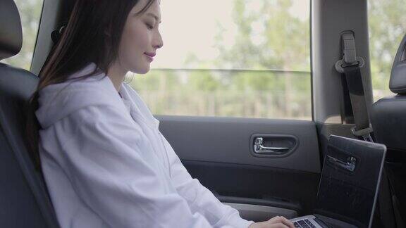 女商人在出租车上一边用笔记本电脑一边打电话坐在汽车后座上用笔记本电脑和手机的女人