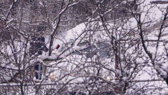 一名司机将汽车从积雪覆盖的树木后面的积雪中清理出来