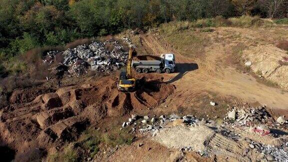 挖掘机将地面装填到自卸卡车上的鸟瞰图