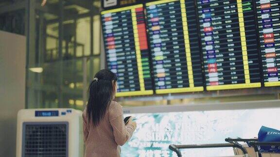 美丽的亚洲女人在国际机场检查她的航班她看了看智能手机查看了一下登机时间