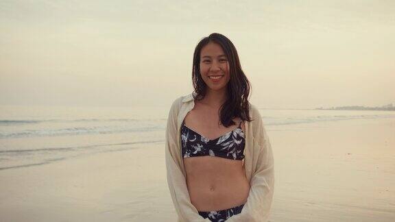 年轻的亚洲女子微笑着看着相机在热带海滩健康积极的生活方式和暑假