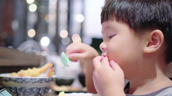 一个亚洲小男孩在日本餐厅吃日本菜