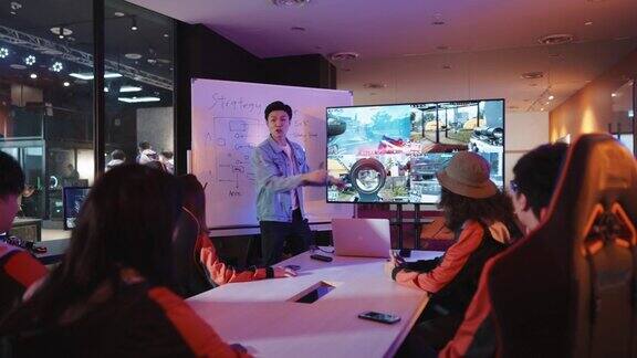 亚洲华人电竞队教练在有白板和电视的会议室里为团队分析电子游戏决赛前的简报策略