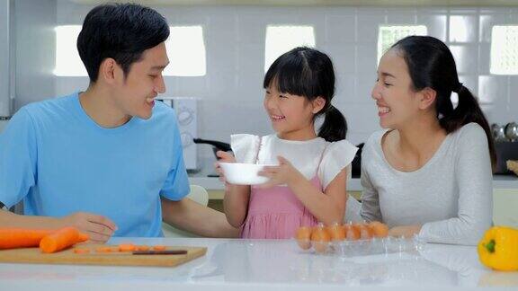 一个快乐的年轻家庭妈妈爸爸和小女孩在厨房里一起做饭泰国家庭