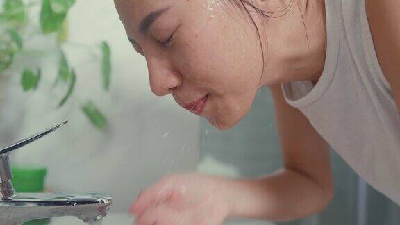 年轻的亚洲女人在家里洗手间的镜子前用泡沫洗脸的特写日常的生活方式