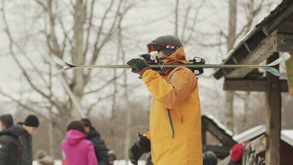 这名男子在冬季度假村的录像中拿着滑雪板