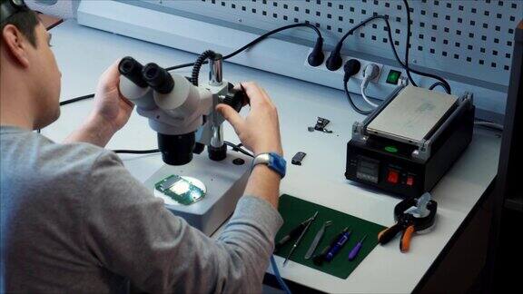 电子研究与服务机构工程师安装显微镜来诊断主板
