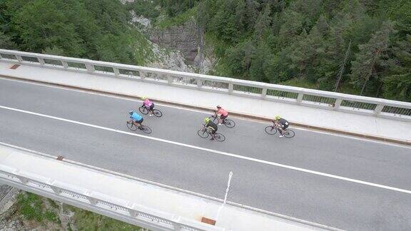 在一个阳光明媚的日子里跟随一群骑自行车的人在高山上穿过一座桥