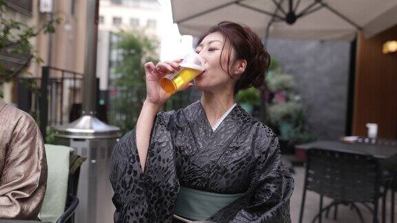 穿着和服在户外咖啡馆喝啤酒的日本女人