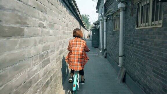 中国北京在胡同里骑自行车的女人