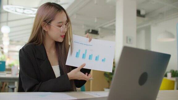 亚洲商业女性使用笔记本电脑与同事在线在线研讨会演示