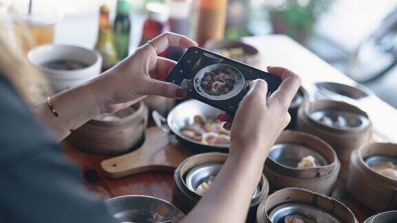 亚洲女人用手机拍桌子上的食物