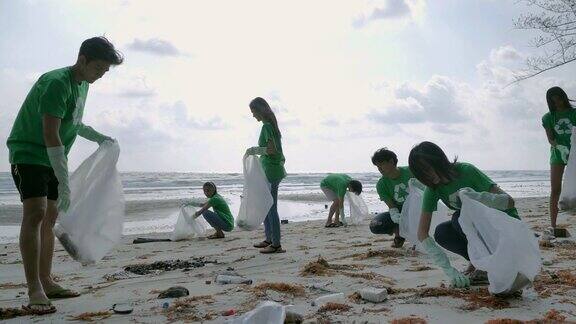 一群快乐的志愿者用垃圾袋清理海滩上的区域志愿、慈善、清洁、人与生态的观念