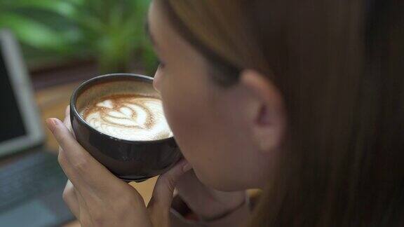 亚洲女商人在咖啡店喝拿铁咖啡的4K特写