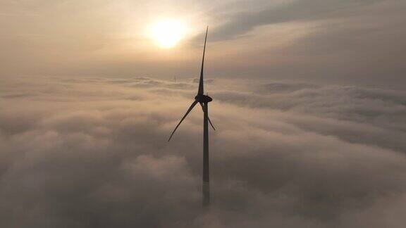 无人机镜头在一个风力涡轮机覆盖着浓雾与日出场景的背景