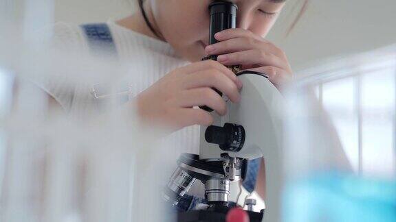 有趣的小女孩在实验室里做实验看显微镜科学和教育教育的主题