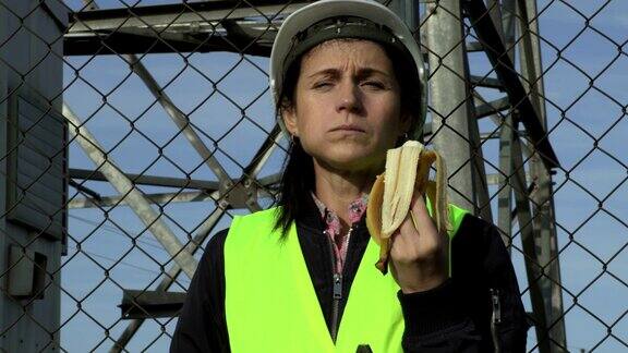 戴头盔的女工程师在休息时吃香蕉