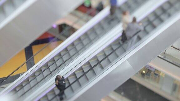 人们在现代化购物中心的自动扶梯上走动倾斜移位镜头拍摄超浅景深