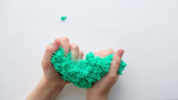 手玩带有气泡的有纹理的黏液拉伸粘稠物质少女手握绿色闪亮的黏液挤压它可爱的女孩把黏糊糊的玩具拉伸到两侧液体的玩具
