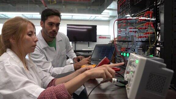 一对工程师学生在实验室里用电气设备做一个项目