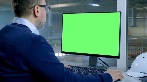 总工程师使用绿色屏幕模型在电脑上工作从她办公室的窗户可以看到工厂里面