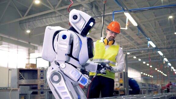 工厂的一名男性员工正在启动一个机器人之后机器人就会启动并开始钻孔