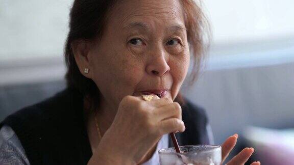 亚洲资深女性饮用冰沙吸管退休概念