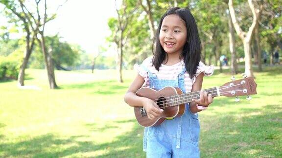亚洲小女孩在花园里弹奏四弦琴