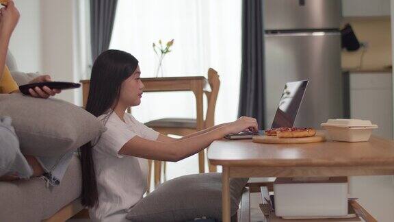 两个女人在客厅里看电视用笔记本电脑工作吃披萨