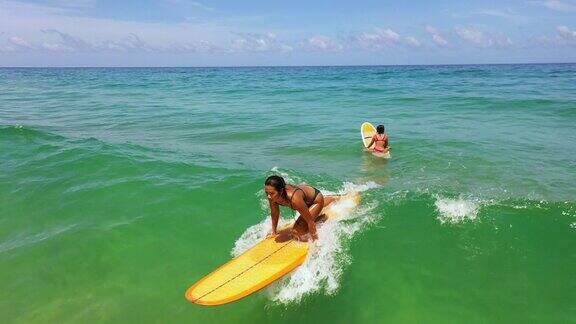 亚洲女性朋友在热带海滩一起冲浪的4K鸟瞰图