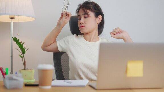 亚洲女性在工作时又累又困女商人在办公室用笔记本电脑头疼疲惫的女人在家里用电脑玩到深夜超负荷和过度工作