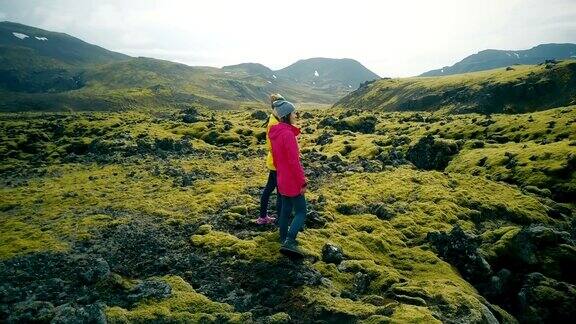 两名妇女在冰岛熔岩上行走的鸟瞰图游客欣赏风景探索领土