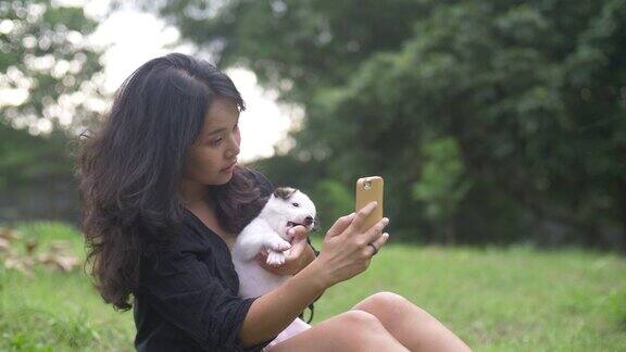 年轻女子与可爱的狗在自然中与相机手机自拍